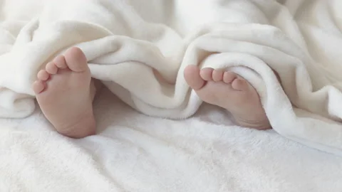 Cute kid boy legs get out from under fluffy coverlet blanket Stock Footage 204923300