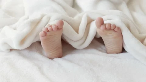 Cute kid boy legs get out from under fluffy coverlet blanket Video stock 204923312