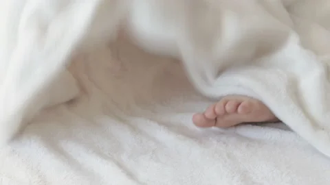 Cute kid boy legs get out from under fluffy coverlet blanket Stockbeeldmateriaal 204923356