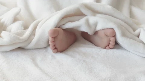 Cute kid boy legs get out from under fluffy coverlet blanket 库存影片 204923370