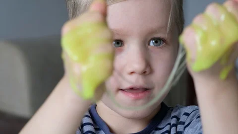 Cute kid boy playing with light green slime. Close up Stock Footage 129332605