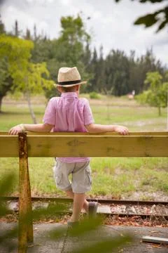 Cute kid boy in a straw hat standing on either side of an old rail fence. Stock Photos