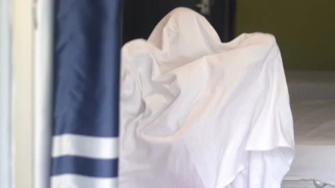 Cute kid child boy wrapped in white blanket or covered on head like a ghost 库存影片 218836730