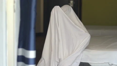 Cute kid child boy wrapped in white blanket or covered on head like a ghost Stock Footage 218836735