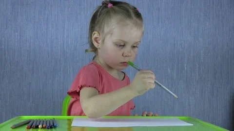 Cute Kid Draws With Crayon Sitting Behind The Green Table Video stock 73546083