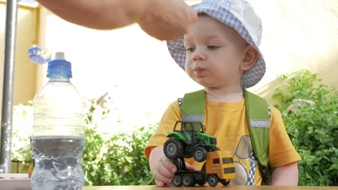 A cute kid eats outdoors in a cafe. He plays with cars and eats cookies with Video stock 76400691