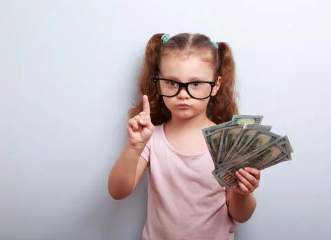 Cute kid girl holding dollars and have an idea how earning much money in cris Stock Photos
