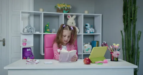Cute kid girl using tablet computer. Young teenage child doing remote homework Stock Footage 194458109