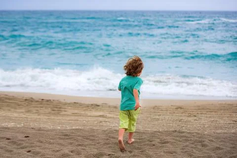 Cute kid having fun and running on sandy beach in summer. Stock Photos