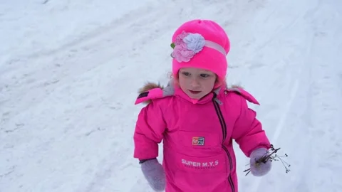 Cute kid in pink winter clothes reaching, holding, and playing with dry twi.. Stock Footage 333581275