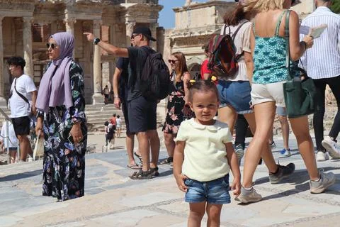 Cute kid pose between the crowded tourists in front of ancient ruins of Celsu Stock Photos