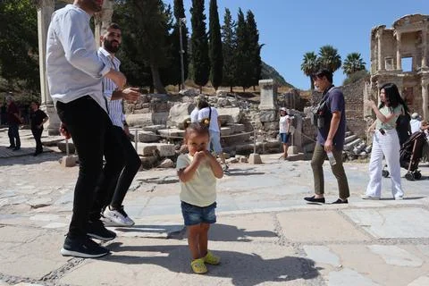 Cute kid pose between the crowded tourists in front of ancient ruins of Celsu Stock Photos