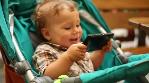 Cute kid with smartphone is dancing in the stroller Stock Footage 65434742
