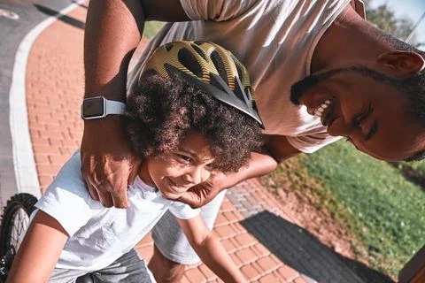 Cute kid smiling while his father fixing his helmet Stock Photos