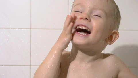 Cute kid (toddler two years old) washing his face and smiling. Bathroom, shower. Vídeos de archivo 102530715