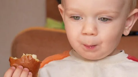 Cute kid two years of eating a muffin at home. Close-up Stock Footage 75042555