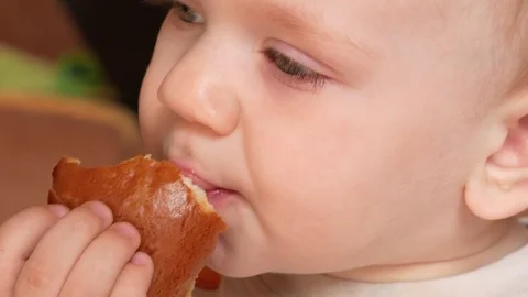 Cute kid two years of eating a muffin at home. Close-up Stock Footage 75042775