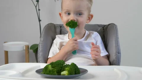 Cute kid ( two years old child, caucasian little boy)  eating broccoli 库存影片 103444612