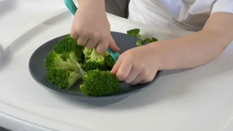 Cute kid ( two years old child, caucasian little boy)  eating broccoli 库存影片 103445992