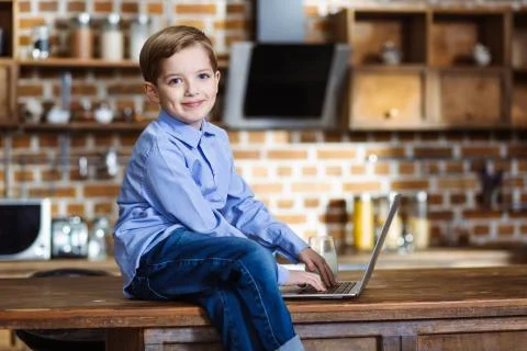 Cute kid using laptop in the kitchen Stock Photos