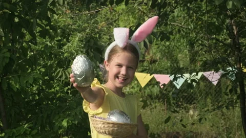 Cute kid wearing bunny ears on Easter day outdoor. Girl holding basket with eggs Video stock 237334423