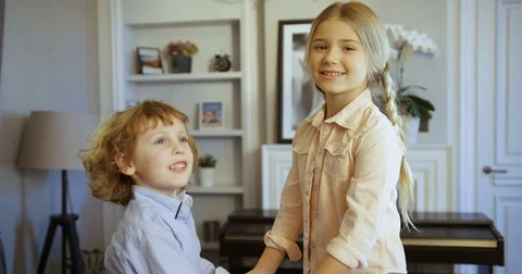 Cute kids having fun. Little boy and girl jumping with holding hands on the sofa Stock Footage 74285148