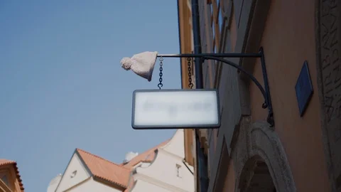 Cute knitted hat with pompom put on a metal sign of a gift shop in Prague 库存影片 115227302