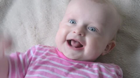 Cute little baby is looking into the camera and is happy on a bed sheet. Stock Footage 63323804