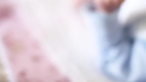 A cute little baby is looking into the camera and is happy on a white bed sheet Stock Footage 73649854