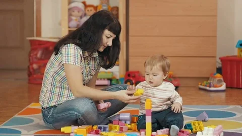 Cute little boy and mother playing with toy blocks at home, in the room, sitt Stock Footage
