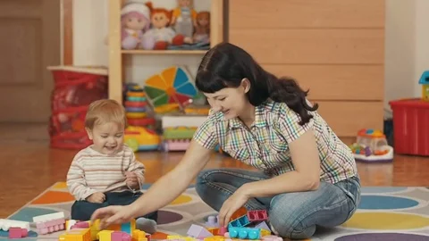 Cute little boy and mother playing with toy blocks at home, in the room, sitt Stock Footage
