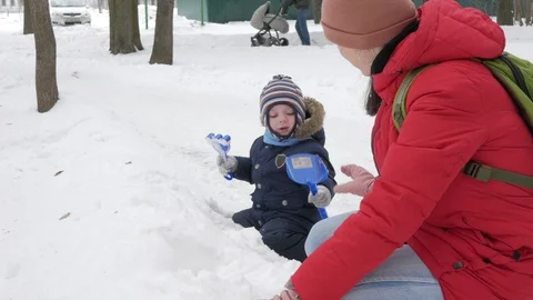 Cute little boy and young mother play in the winter with snow in the park. Blue Stock Footage 86821153
