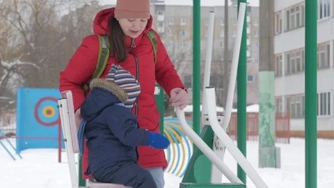 A cute little boy and a young mother are engaged in outdoor exercise equipment Stock Footage 86830981