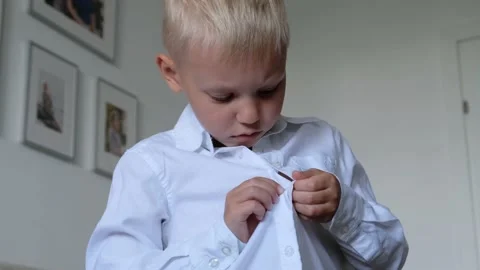 Cute little boy button up white shirt, making ready for school. Childhood Stock Footage 163440678