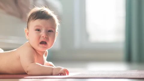 Cute little boy crying lying on his stomach on the floor. Foto stock
