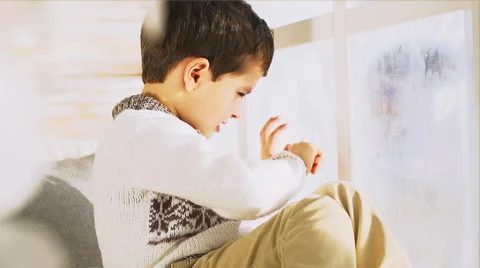 Cute little boy draws on a window in the winter Stock Footage 58826937
