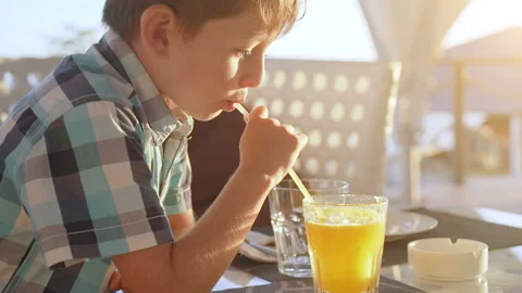 Cute little boy drinking fresh orange juice from glass in city cafe Stock Footage 95844776