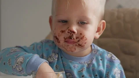 A cute little boy eats chocolate with pleasure smiling and laughing close-up Stock-Footage 168734290