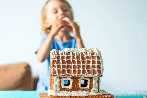 Cute little boy eats gingerbread house and having fun. Kid enjoy Christmas Stock Photos