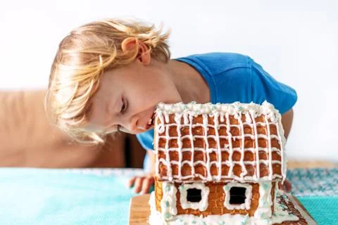 Cute little boy eats gingerbread house and having fun. Kid enjoy Christmas Stock Photos