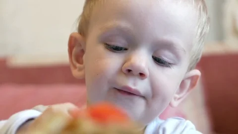 A cute little boy eats porridge with pieces of meat at a children's table. home Stock Footage 81237186