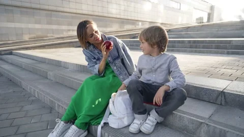 Cute little boy going to school with his mother outdoors. Happy mom sitting on Stock Footage 140258573