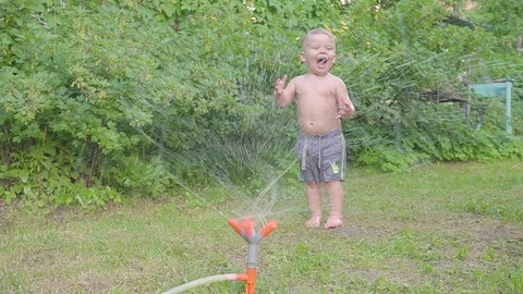 Cute little boy having fun outside with water sprinkler in summer garden. Slow Video stock 90495828