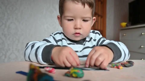 Cute little boy having fun with colorful modeling clay at a daycare, close up Stock Footage 171381528