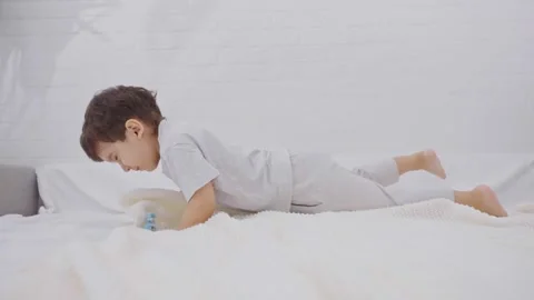 Cute little boy having fun jumping in the bedroom Stock-Footage 244355807