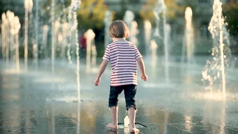 Cute little boy having fun with water in city fountain. Video stock 279605096