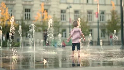 Cute little boy having fun with water in city fountain. Stockbeeldmateriaal 294618011