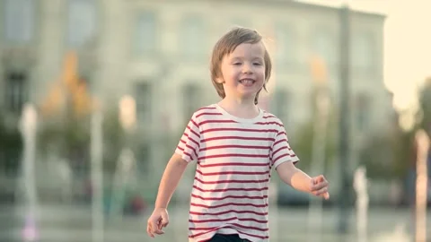 Cute little boy having fun with water in city fountain. 스톡 동영상 310514353
