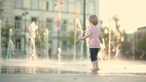Cute little boy having fun with water in city fountain. 스톡 동영상 310528189