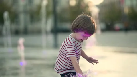 Cute little boy having fun with water in city fountain. 스톡 동영상 315260070
